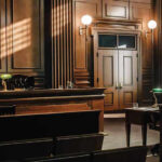 Court BLOCKS Abortion Pill Mail NATIONWIDE Empty courtroom with wooden interior and green lamps.