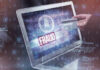 Person holding credit card near laptop displaying Fraud.