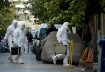 Investigators in hazmat suits carrying equipment cases.
