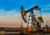 An oil pump jack operating against a sunset backdrop