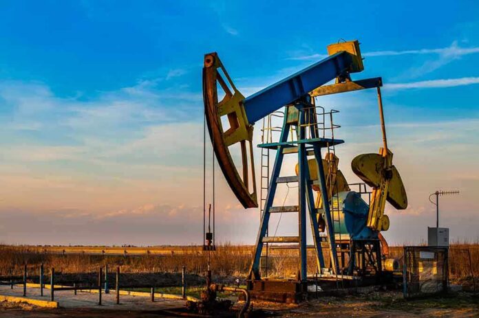 An oil pump jack operating against a sunset backdrop