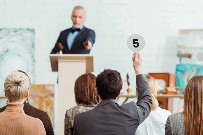 Auctioneer at podium as bidder raises numbered paddle