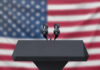 Weekend Carnage Sparks Federal Clash Podium with microphones, American flag background.
