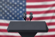 Weekend Carnage Sparks Federal Clash Podium with microphones, American flag background.