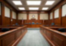 Empty courthouse courtroom with wooden benches and chairs.