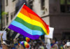 People holding and waving a rainbow flag.