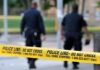 Police officers walking past caution tape at a crime scene