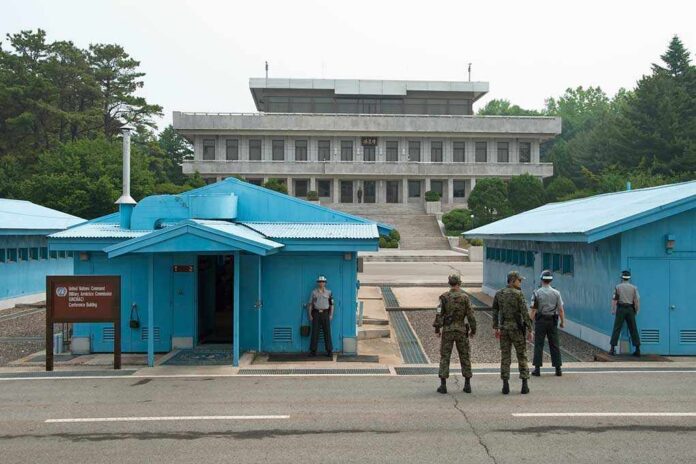 Military personnel standing near blue buildings at a border crossing