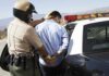 Wealthy Heir Caught Menacing a Synagogue Police officer arresting a suspect near a patrol car
