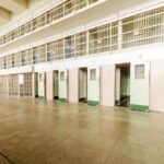 Interior view of a prison cell block with empty cells and security bars