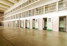 Interior view of a prison cell block with empty cells and security bars
