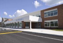 School Board Firestorm: Graves, Dogs, Felony? Modern school building with large windows and a clear sky