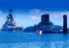 A submarine and a warship in the ocean under a blue sky