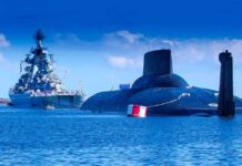 A submarine and a warship in the ocean under a blue sky
