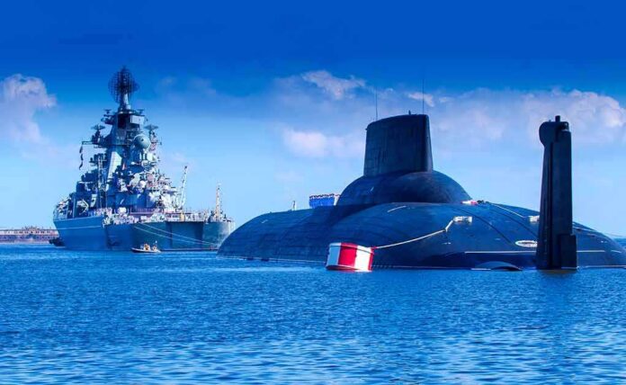 A submarine and a warship in the ocean under a blue sky