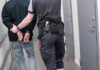 FBI Now Investigating Houston ICE Shooting — While Video Stays Sealed Officer escorting handcuffed person down hallway.