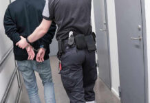 FBI Now Investigating Houston ICE Shooting — While Video Stays Sealed Officer escorting handcuffed person down hallway.