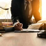 Lawyer writing at desk with scales and gavel