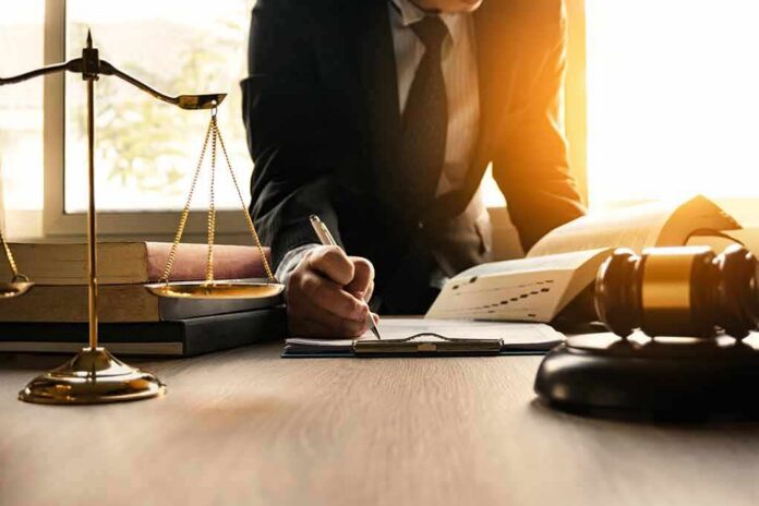 Lawyer writing at desk with scales and gavel