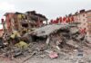 Death Toll Explodes — Officials Admit More Rescue workers in orange uniforms on a collapsed building site after an earthquake
