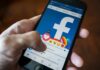 Hand using smartphone with Facebook reactions on screen