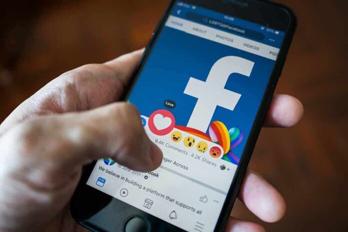 Hand using smartphone with Facebook reactions on screen