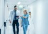 Doctors walking in a hospital corridor reviewing a tablet