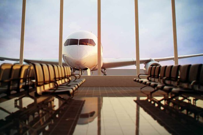 shutterstock_124713472-1 Airplane seen through terminal windows with empty gate seating
