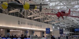 airport security checkpoint with passengers and hanging vintage airplanes