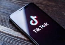 Smartphone displaying the TikTok app logo on a wooden surface