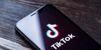 Smartphone displaying the TikTok app logo on a wooden surface