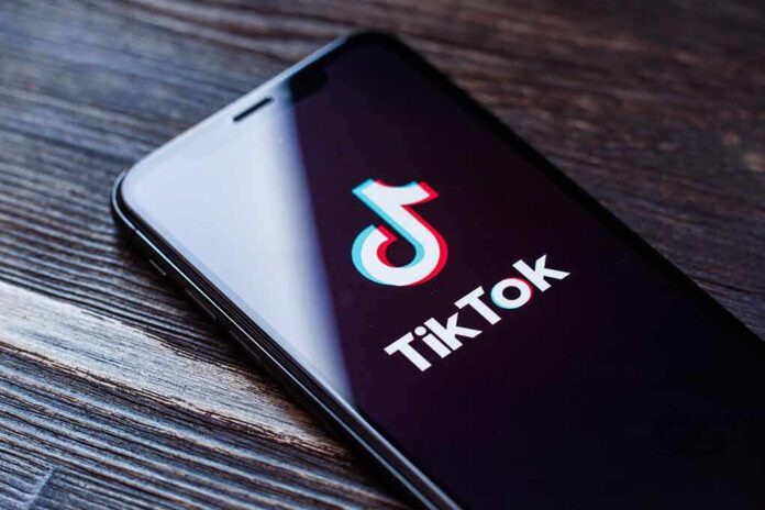 Smartphone displaying the TikTok app logo on a wooden surface
