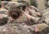 U.S. soldiers in camouflage uniforms saluting