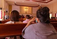 people seated in church pews facing a cross