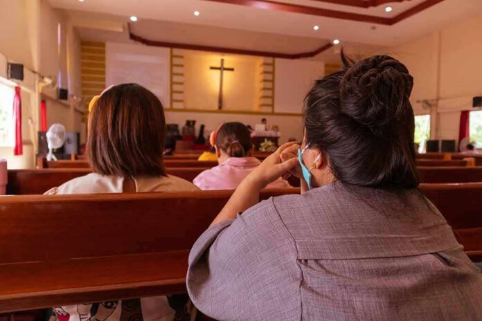 shutterstock_1773600770 people seated in church pews facing a cross