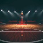 Basketball hoop on an empty indoor court under bright arena lights