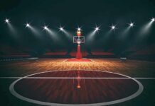 Basketball hoop on an empty indoor court under bright arena lights