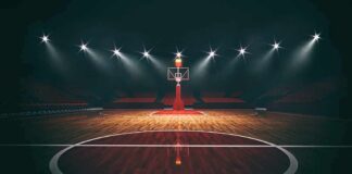 Basketball hoop on an empty indoor court under bright arena lights