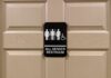 All-gender restroom sign on a beige paneled door