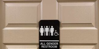 All-gender restroom sign on a beige paneled door