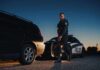 Police officer standing near patrol car during twilight traffic stop