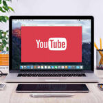 YouTube logo on a laptop screen on desk.