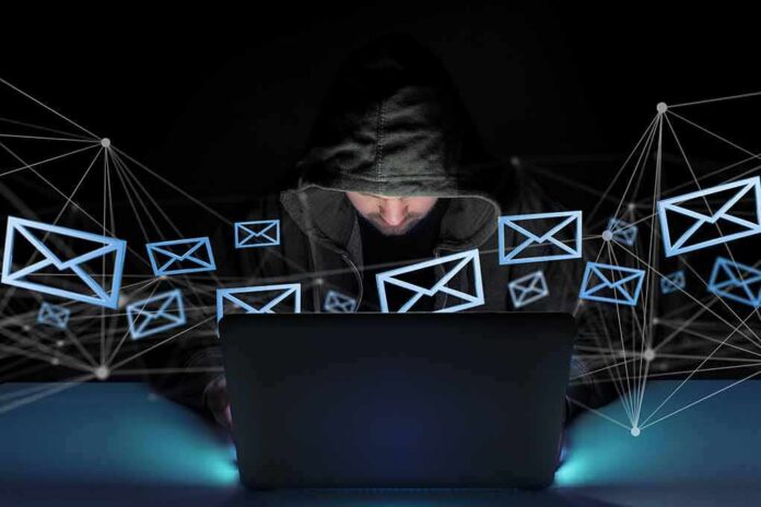 Hooded person using a laptop surrounded by email icons