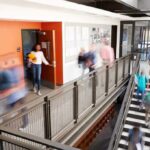 Students walking through a modern school hallway and stairwell