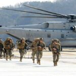Marines Raise Stakes For Technical Recruits Soldiers disembark and walk past a large military helicopter