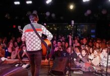 Tour Opener Boils Over After Flag Raise Guitarist performing on stage facing a cheering crowd