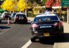 Police cars with lights on near school buses on a city street