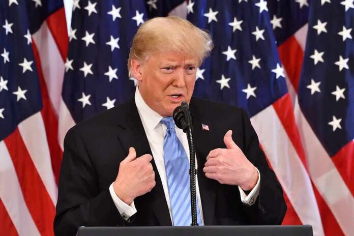 man in suit speaking at podium with US flags behind