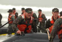 Alexander Vinokourov and Bill Bergey among soldiers moving an inflatable boat in surf