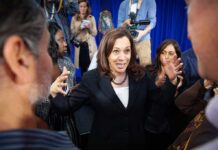 Woman in black blazer speaking animatedly to a crowd